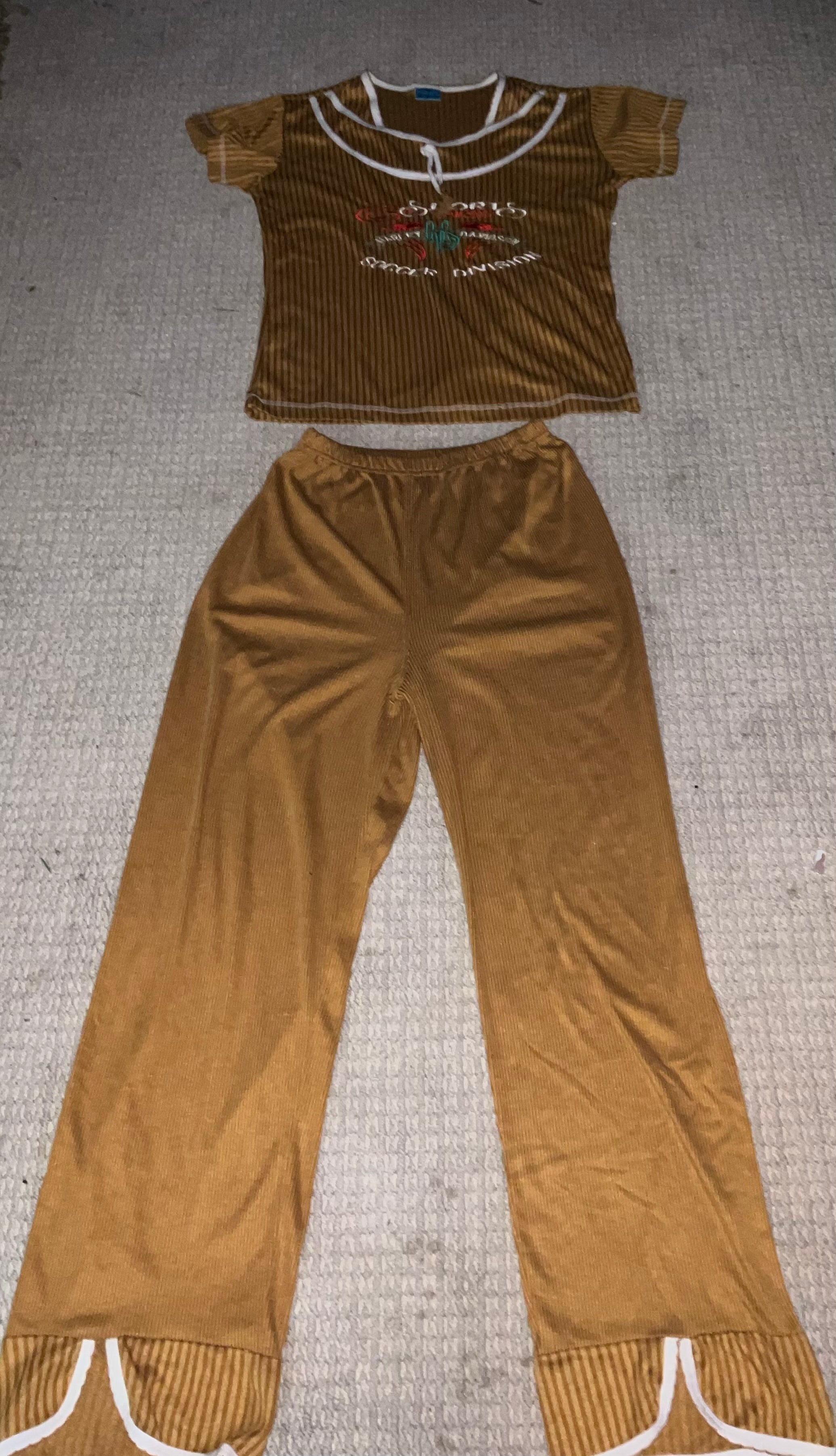 Brown velour two-piece set with crop top and wide leg pants laid flat showing white contrast trim and embroidered graphic