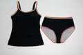 Black two-piece tankini swimsuit with pink and yellow zigzag trim on clean white background